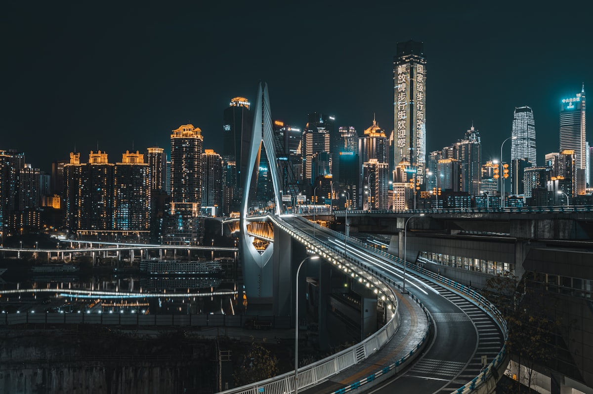 An elevated road curves toward Qiansimen Bridge amid Chongqing's night skyline