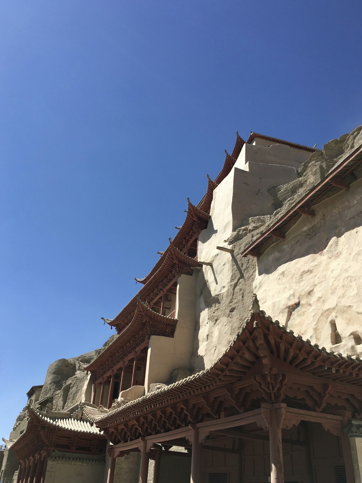 Wooden temple eaves of the Mogao Grottoes against a clear sky in Dunhuang