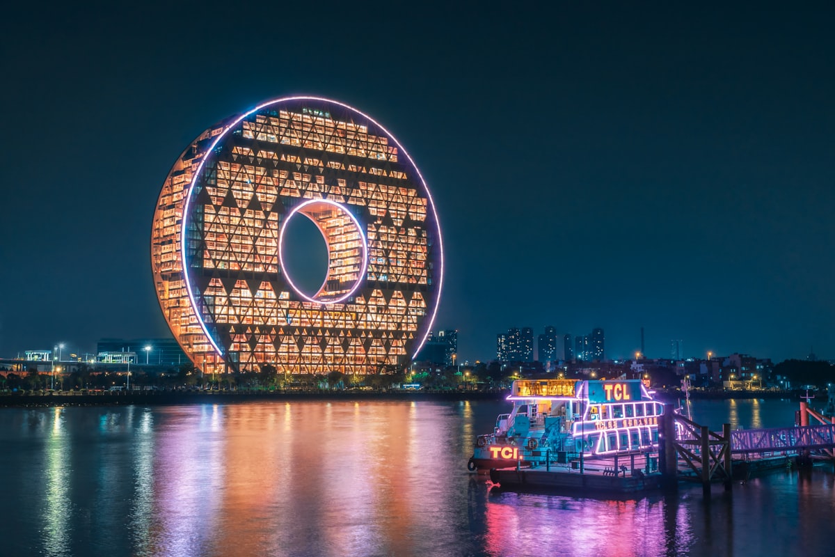 The circular Guangzhou Circle building glowing above the Pearl River at night