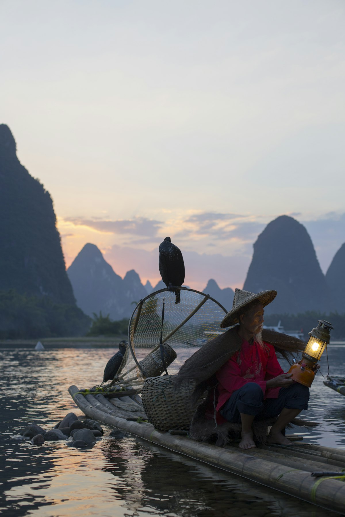 Cormorant fisherman with his birds on a bamboo raft at dusk near Guilin