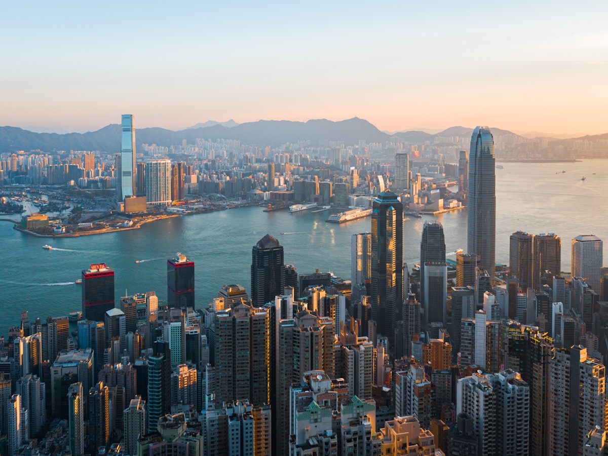 Morning light over Hong Kong Island's dense high-rises, with Victoria Harbour and Kowloon beyond