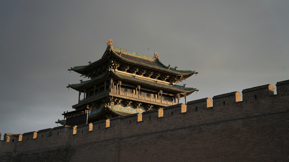 A gate tower rises above Pingyao's fortified brick city wall at dusk