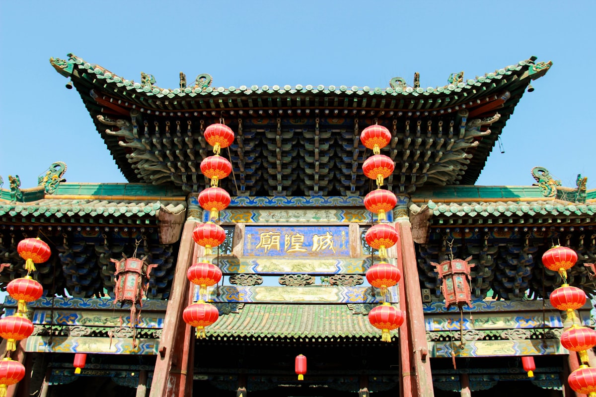 Red lanterns frame the ornate gate of the City God Temple in Pingyao