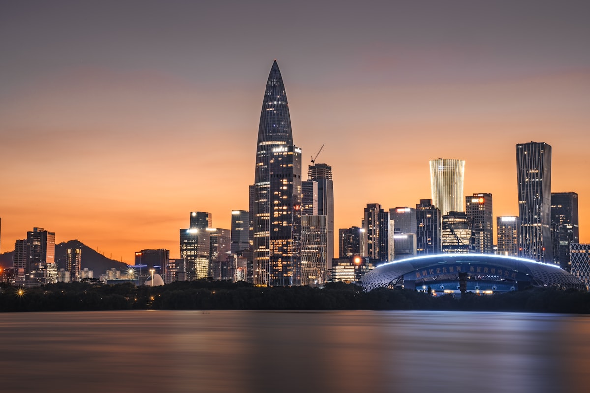 Shenzhen Bay Sports Center and the Houhai skyline at sunset across calm water