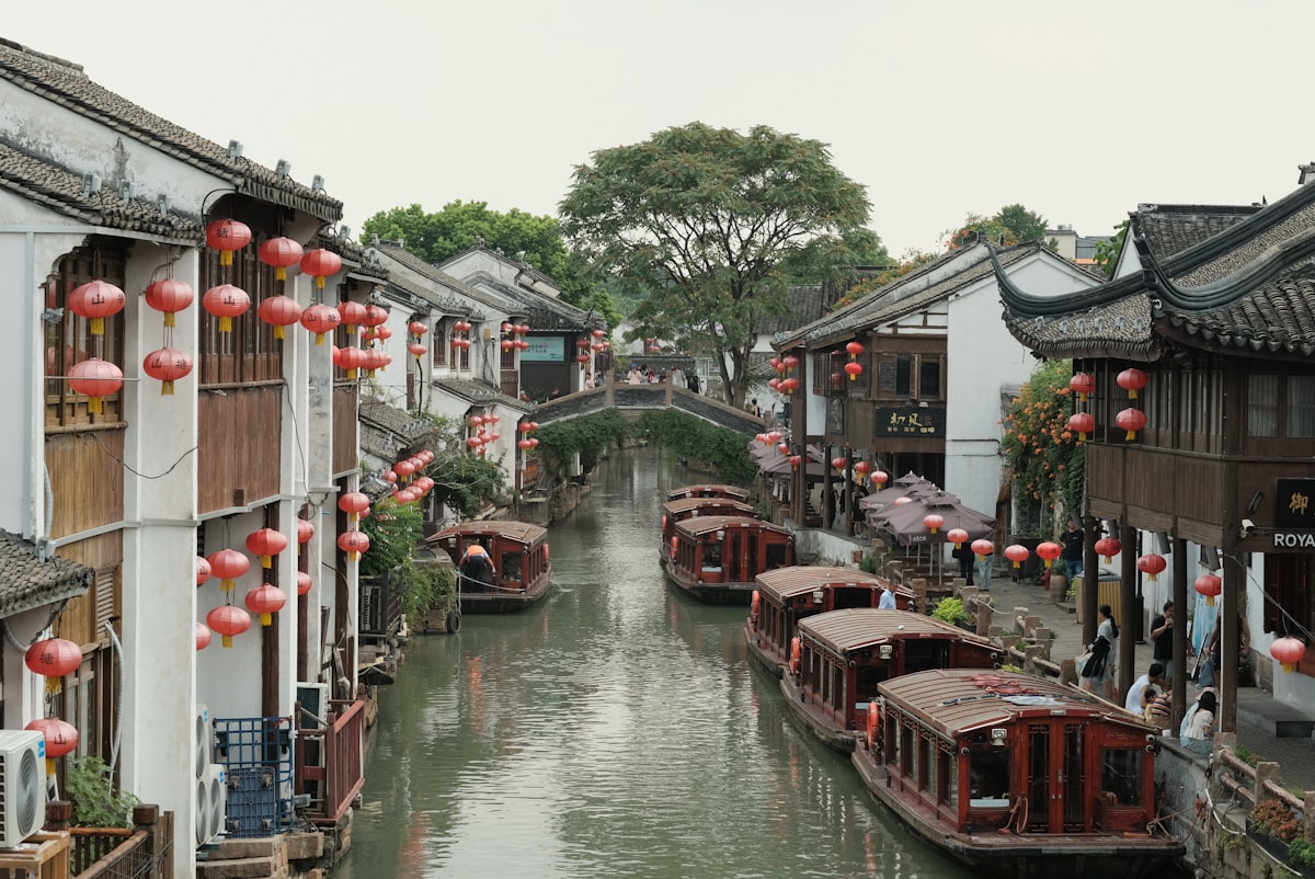Wooden boats and red lanterns along a canal and stone bridge in Suzhou's old town