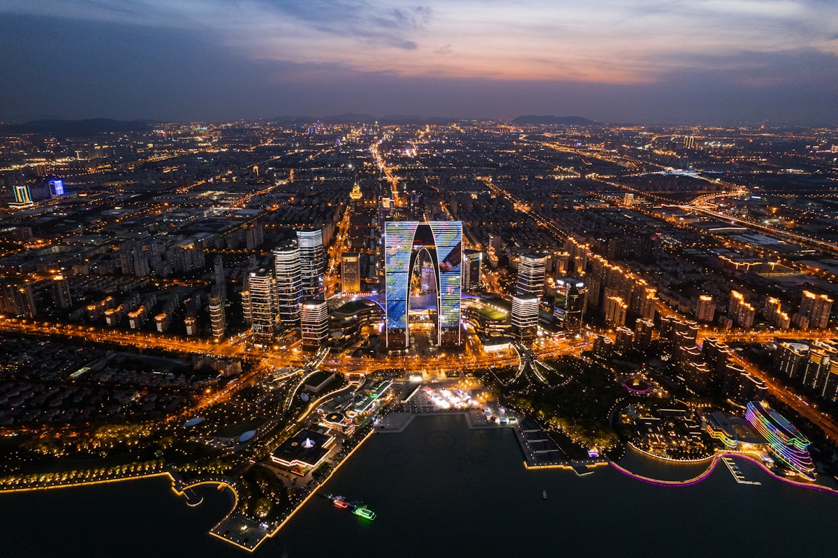Dusk aerial of Suzhou with the Gate of the Orient glowing above the city grid