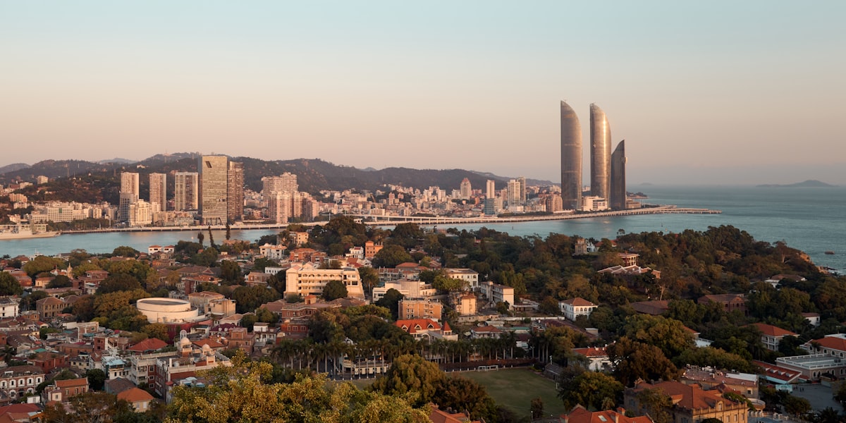 Sunset over Gulangyu Island rooftops, with Xiamen's twin towers on the horizon