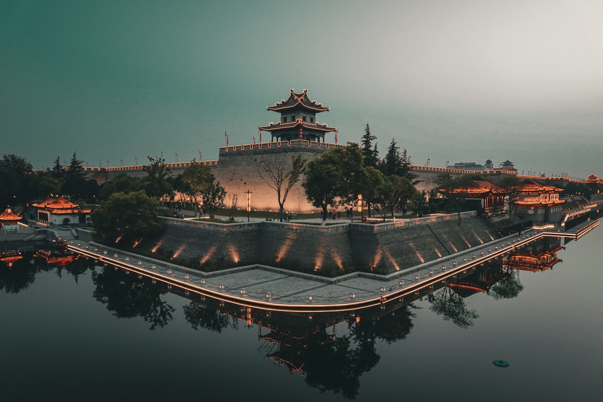 Ming-era city wall and corner watchtower reflected in the moat at dusk, Xi'an