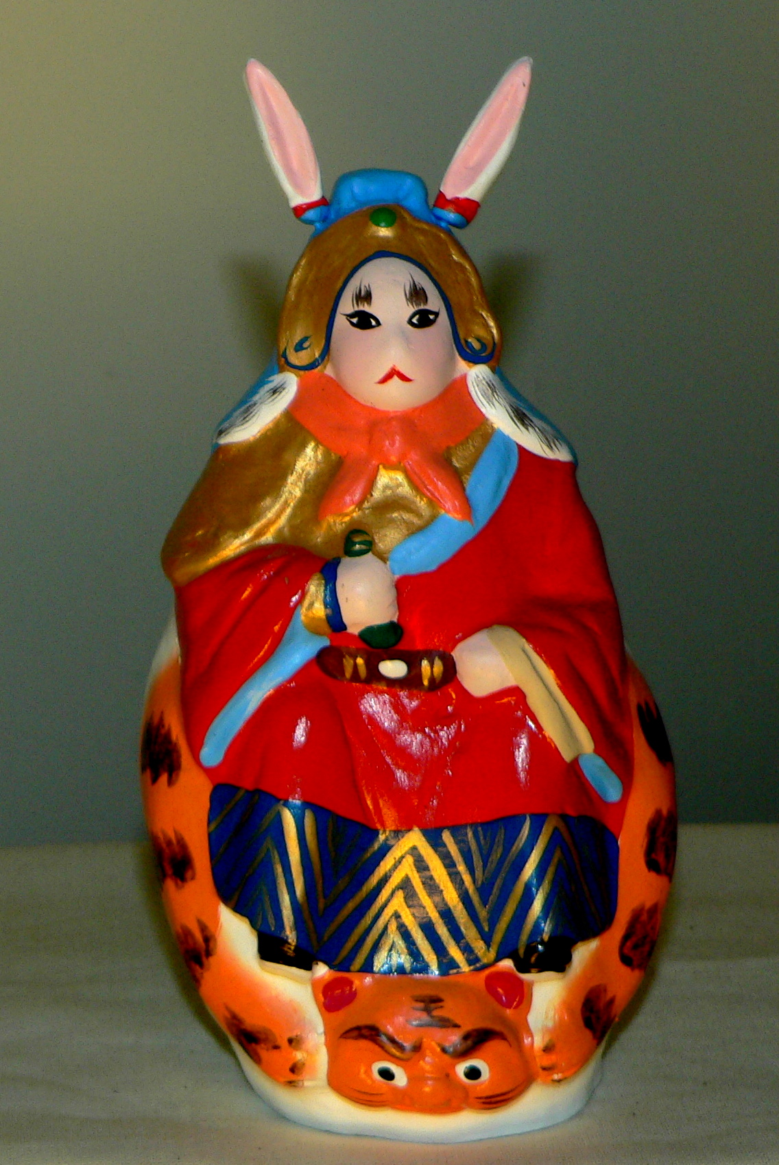 A painted clay Tu'erye figurine: rabbit ears on an armoured human body in red, gold and blue robes