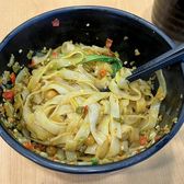 Flat Changsha rice noodles tossed with pickled beans and chilli oil in a dark blue bowl