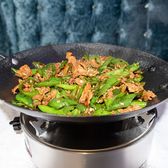 A wok of pork strips stir-fried with sliced green chillies, steaming over a tabletop burner.