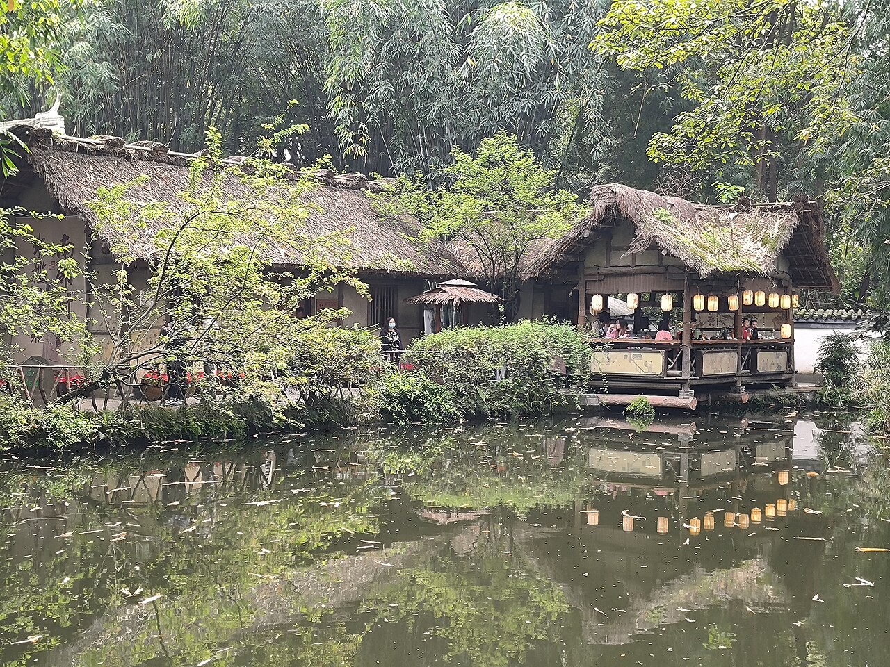 Thatched buildings and bamboo reflected in a pond at Du Fu's Thatched Cottage, Chengdu