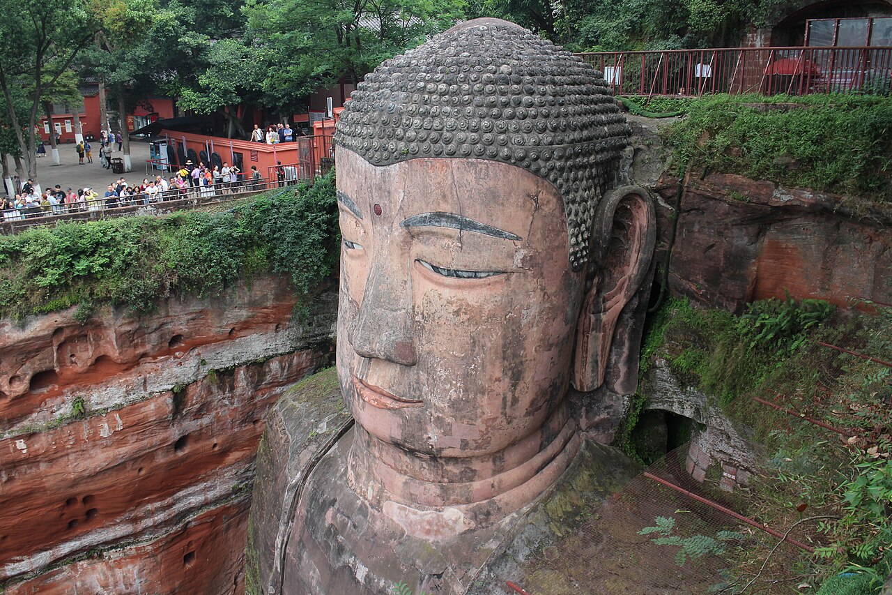 The head of the Leshan Giant Buddha carved into the cliff, visitors on the stairway beside it