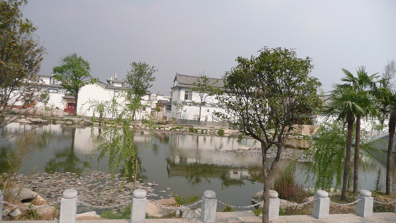 Whitewashed Bai houses and willows reflected in a pond at Xizhou