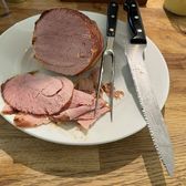 Slices of cured Yunnan ham on a plate with the carving knives beside it