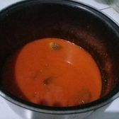 A dark pot of Dali sour fish hotpot broth on the burner