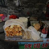 A street stall selling bagged rushan cheese beside a grill