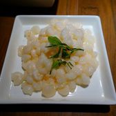 Small peeled shrimp heaped on a square plate with a sprig of tea leaves