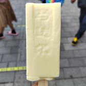 A hand holding a Madieer ice bar on a Harbin street