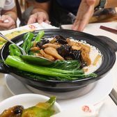 A black claypot of rice topped with greens, being served at the table