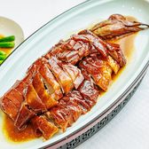 Chopped roast goose on an oval plate with a row of greens beside it