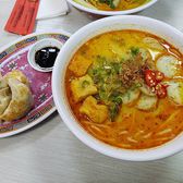 Pan-fried buns beside a bowl of red soup on a patterned tray