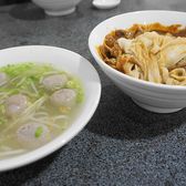 A bowl of satay noodles beside a bowl of fish balls