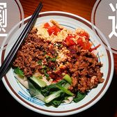 A bowl of biangbiang noodles under minced meat, chilli and greens