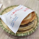 A roujiamo in its paper wrapper on a plate