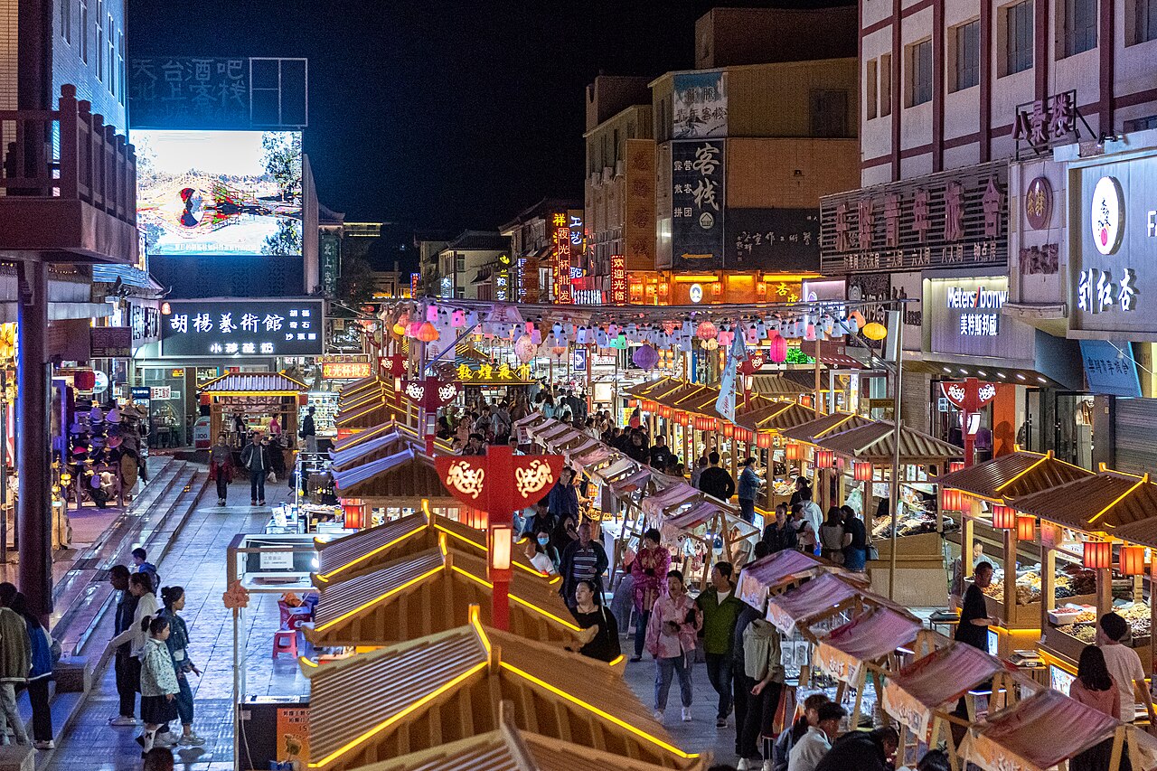 Lit stalls and crowds along the Dunhuang night market street after dark