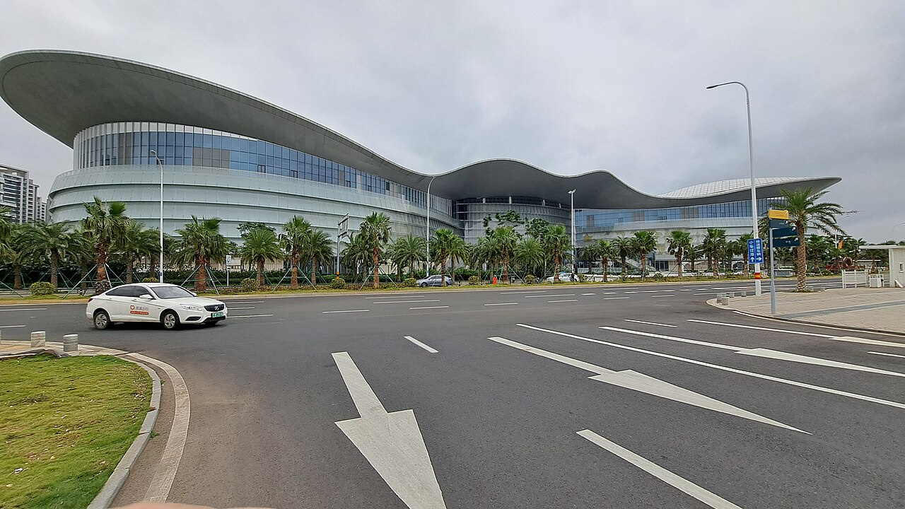 The sweeping wave-shaped roof of Haikou International Duty-Free City above its approach road.