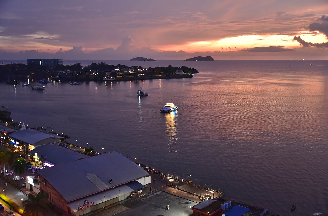 The Kota Kinabalu waterfront at dusk, with fishing boats and ferries moored along the Sabah capital's harbourfront.