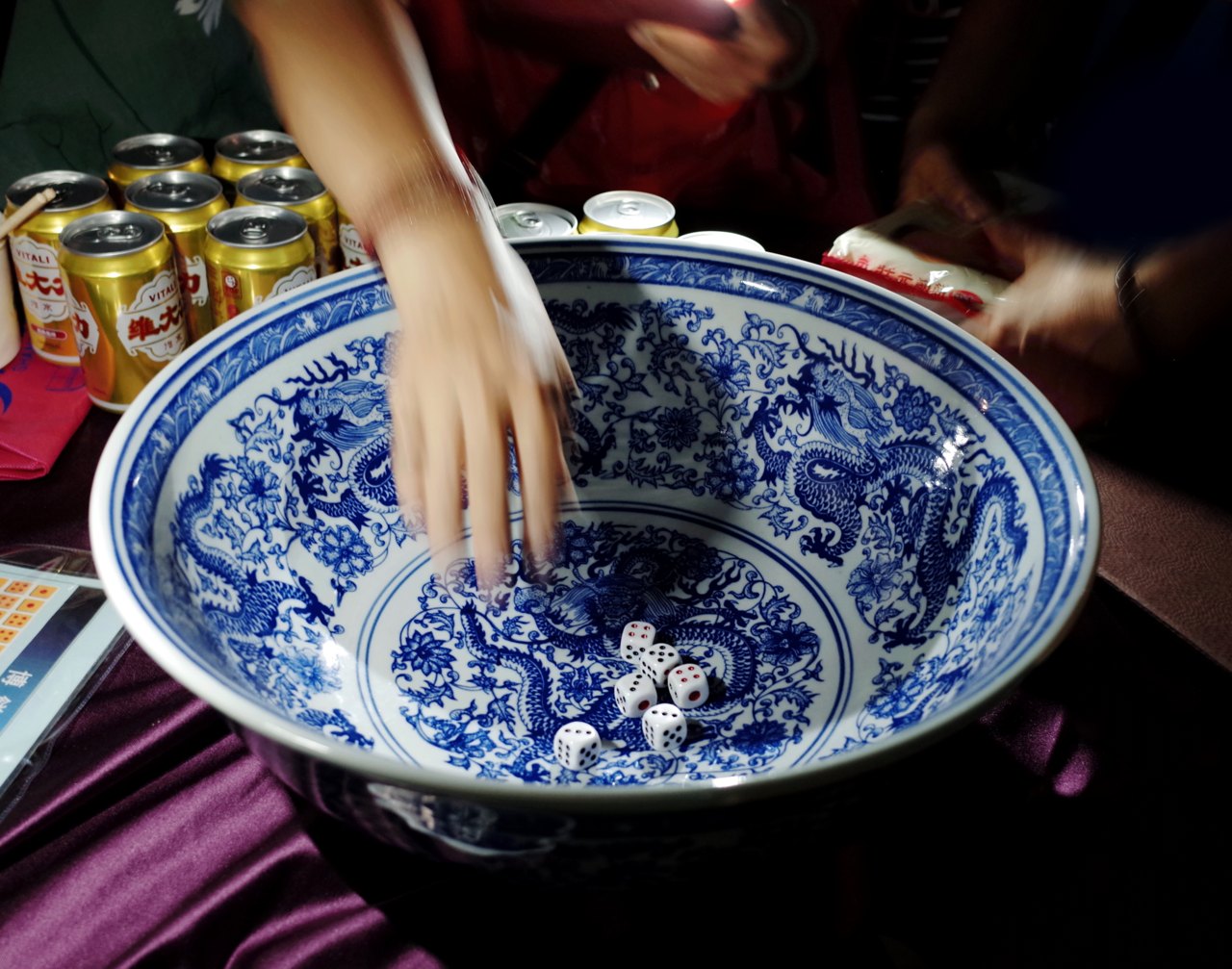 Players rolling six dice into a bowl at a mooncake gambling (bo bing) table