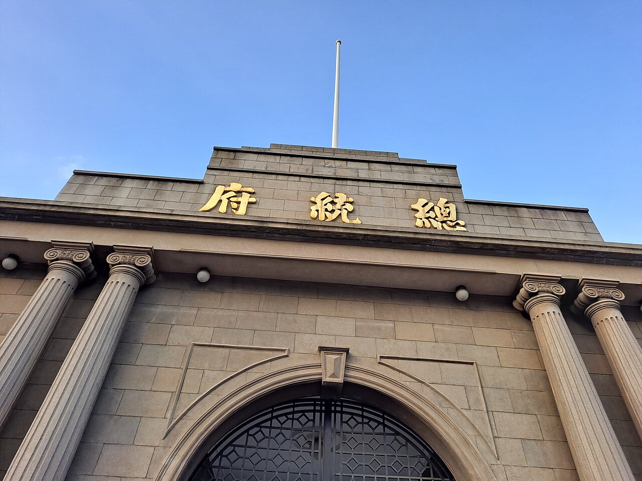 The stone gatehouse of the Presidential Palace in Nanjing, Roman columns flanking the arched gate and gilded Chinese characters 总统 府 across the lintel