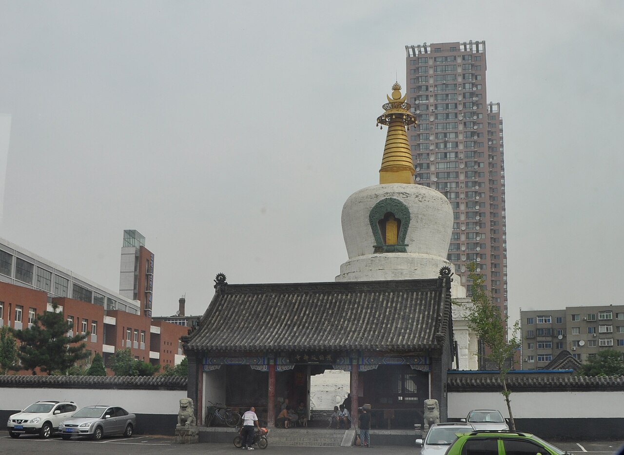 The white Buddhist stupa of the West Pagoda rising over the streets of Xita, apartment towers behind it.