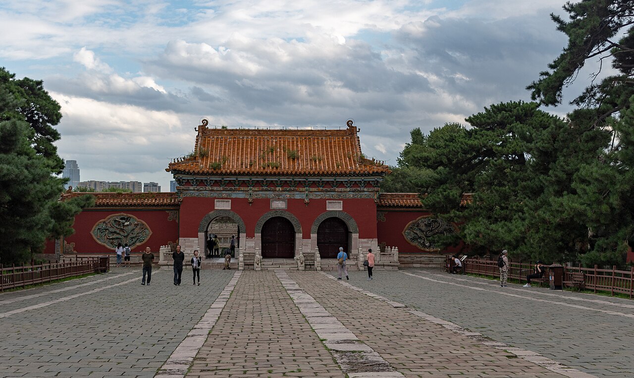 The red ceremonial gate of Zhao Mausoleum set among centuries-old pine trees inside Beiling Park.