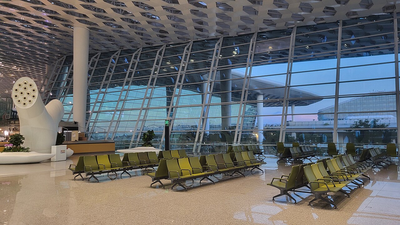 The white honeycomb-patterned facade of Terminal 3 at Shenzhen Bao'an International Airport seen from the approach road.