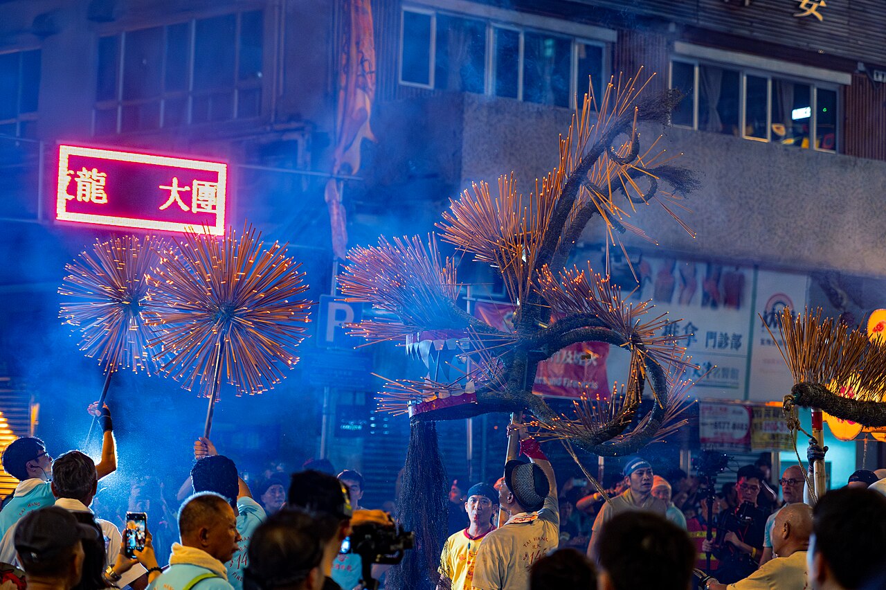 The Tai Hang fire dragon, a long straw dragon covered in glowing incense sticks, weaving through a Hong Kong street at night
