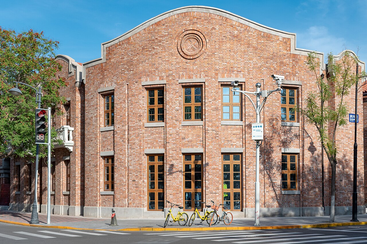 A red-brick 1920s mansion on a leafy corner of the Five Great Avenues, shared bikes parked outside.