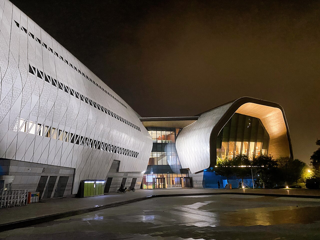 The sweeping white curves of the National Maritime Museum lit at night above its entrance plaza.