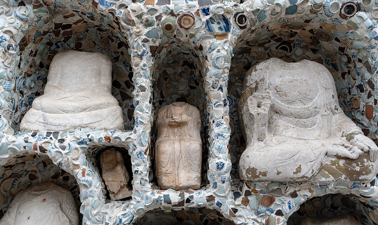 Statues set into wall niches entirely crusted with blue-and-white porcelain shards at the Porcelain House.