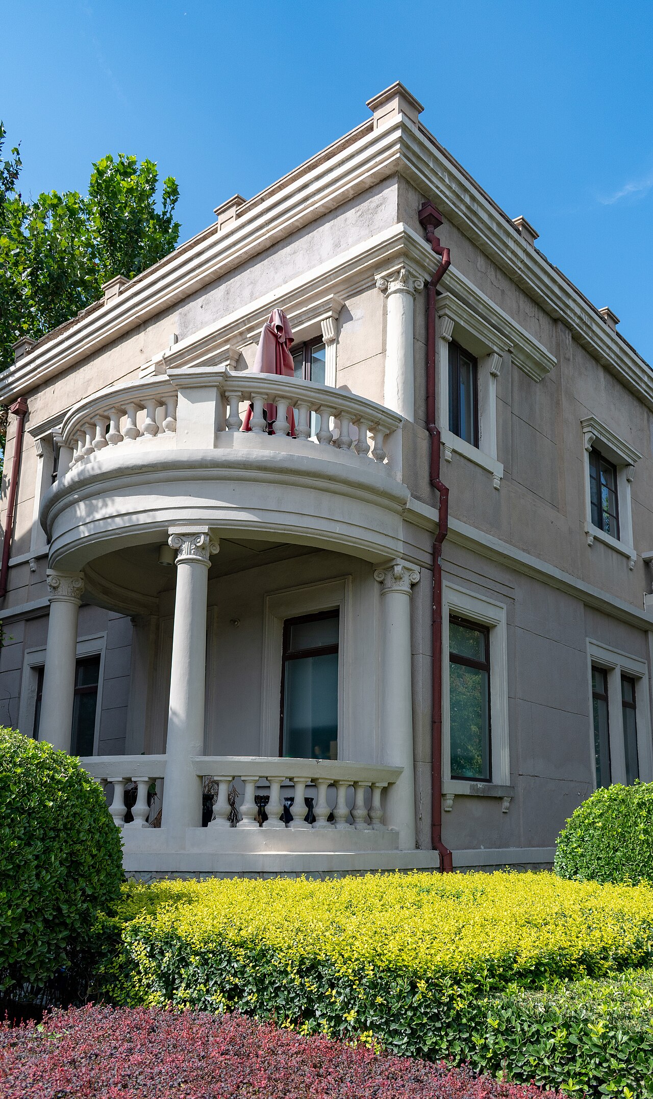 A white Italianate villa with a curved balcony and clipped hedges in the Italian Style Town.