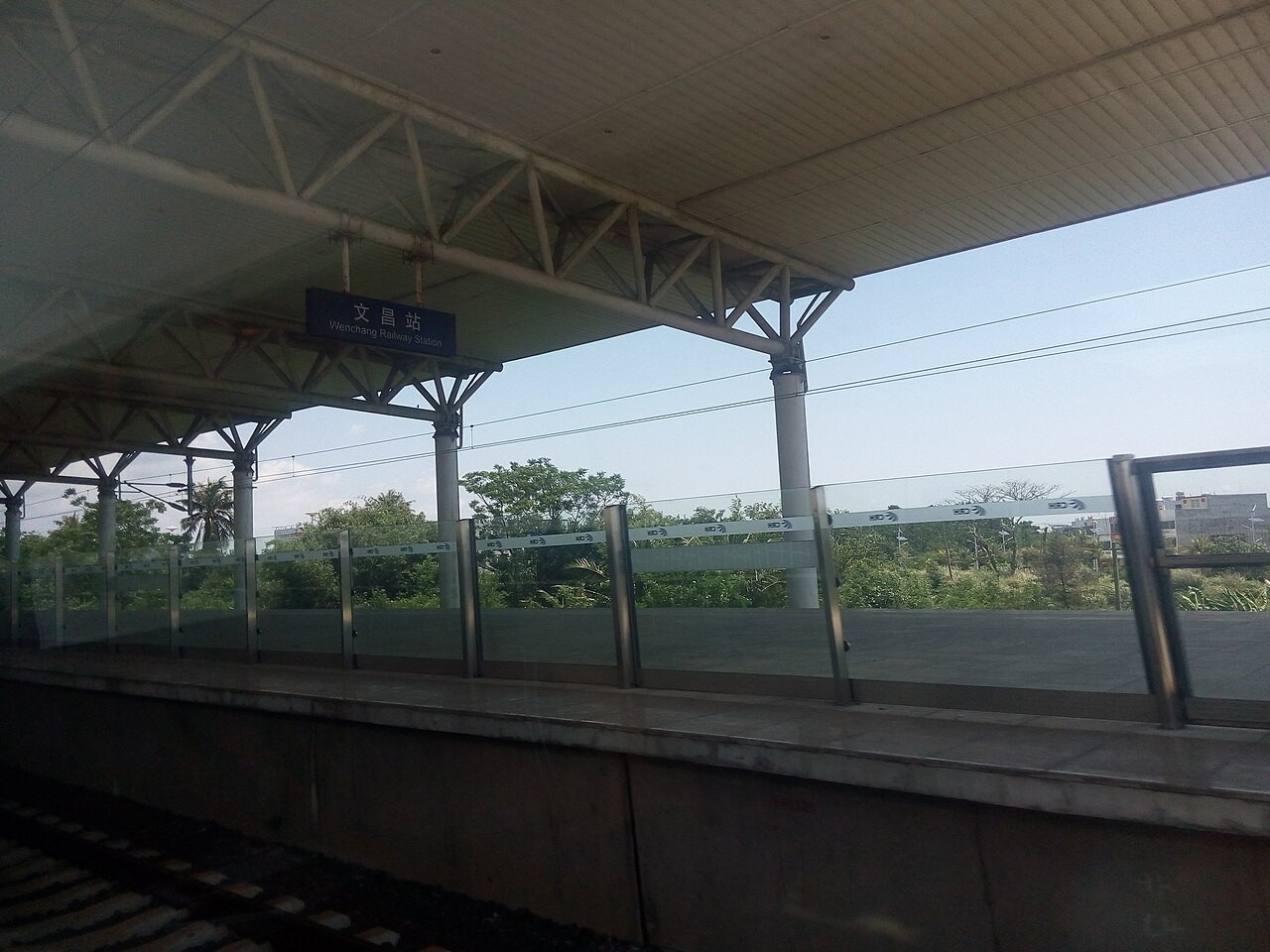 The platform at Wenchang Railway Station, the station name shown in Chinese and English on a blue sign under the canopy.