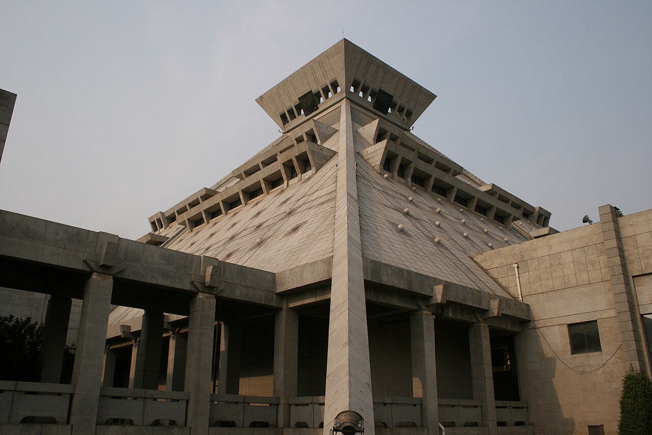 The distinctive pyramidal main hall of Henan Museum against a pale sky.