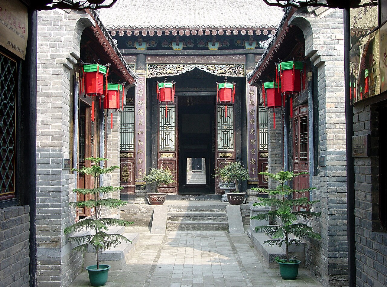A grey-brick courtyard gate hung with red lanterns inside the Kangbaiwan manor.