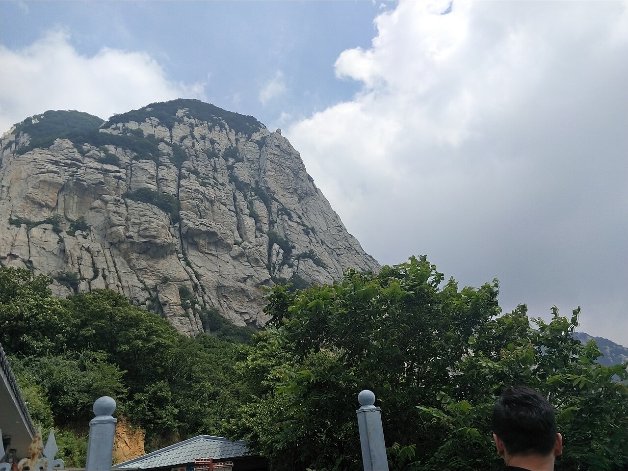 The bare granite dome of Mount Song rising over the tree line under drifting clouds.