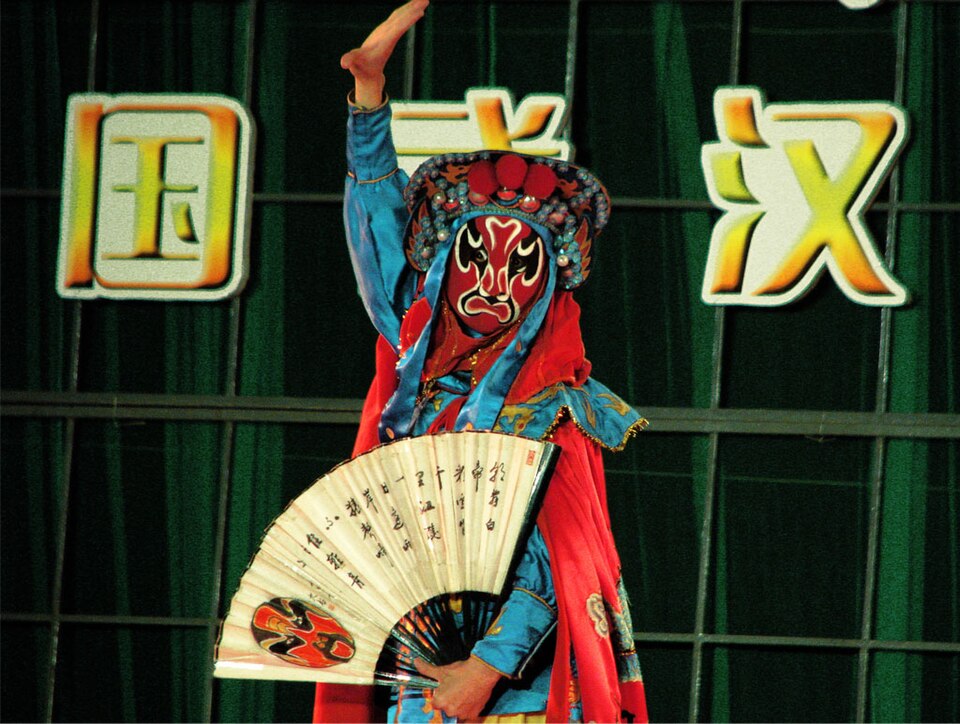 A masked face-changing performer mid-show at a Sichuan opera night