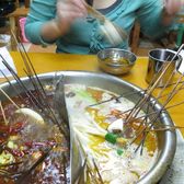 Diners lifting skewers out of a metal chuanchuan hotpot