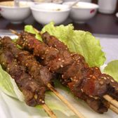 Grilled lamb skewers laid out on lettuce leaves