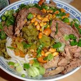 A bowl of Guilin rice noodles under sliced beef and spring onion